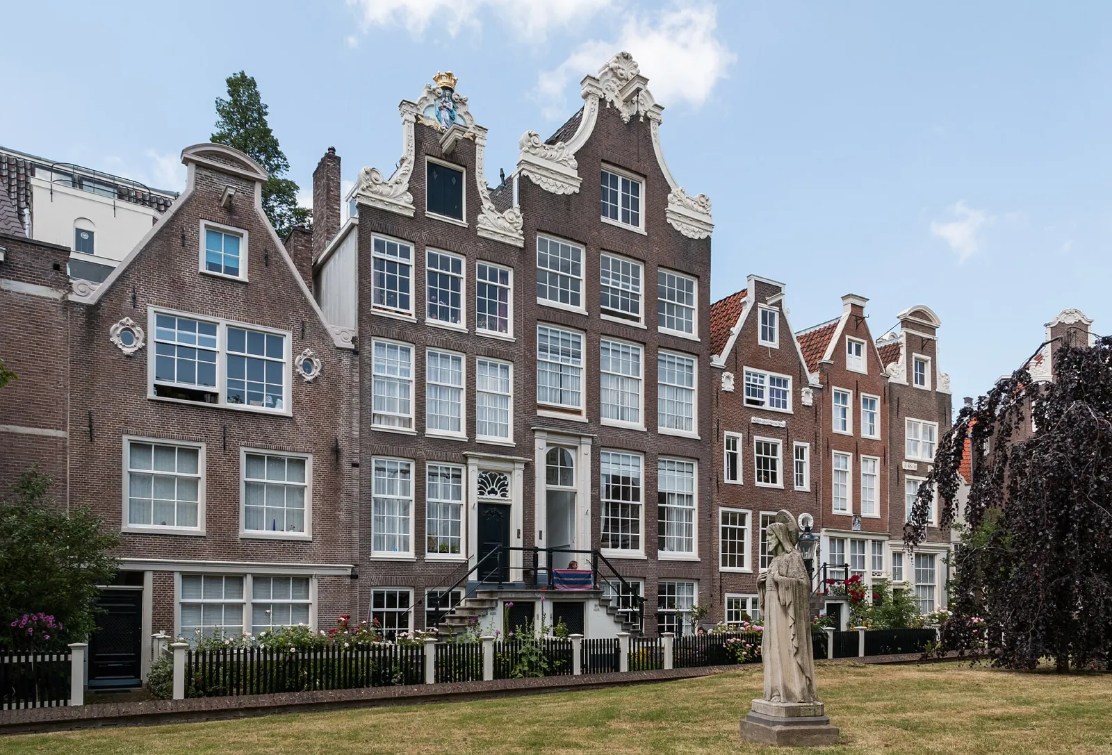 Casas históricas del patio del Begijnhof con la estatua de una beguina