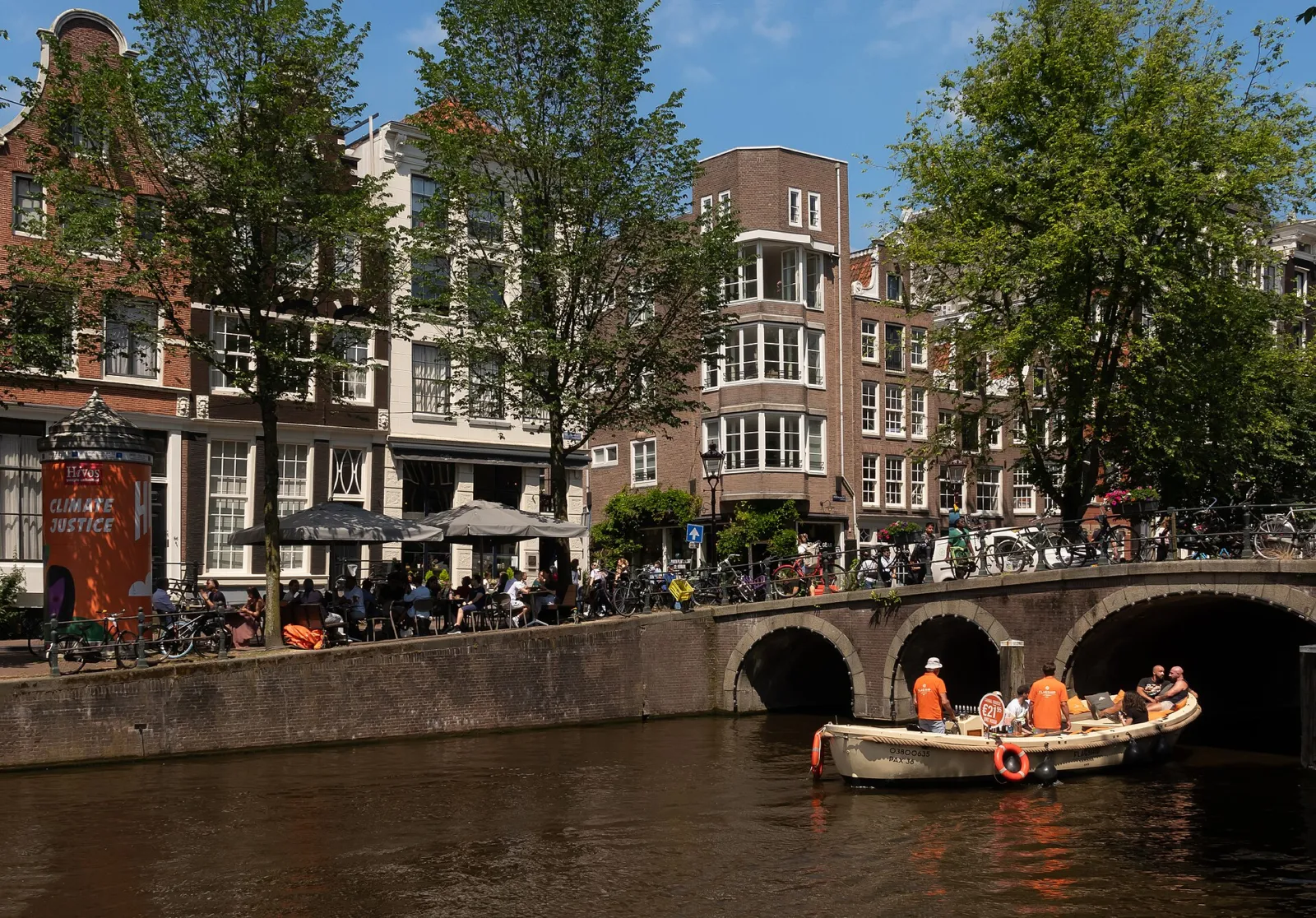 Puente sobre el canal Herengracht con casas de canal y una barca de paseo