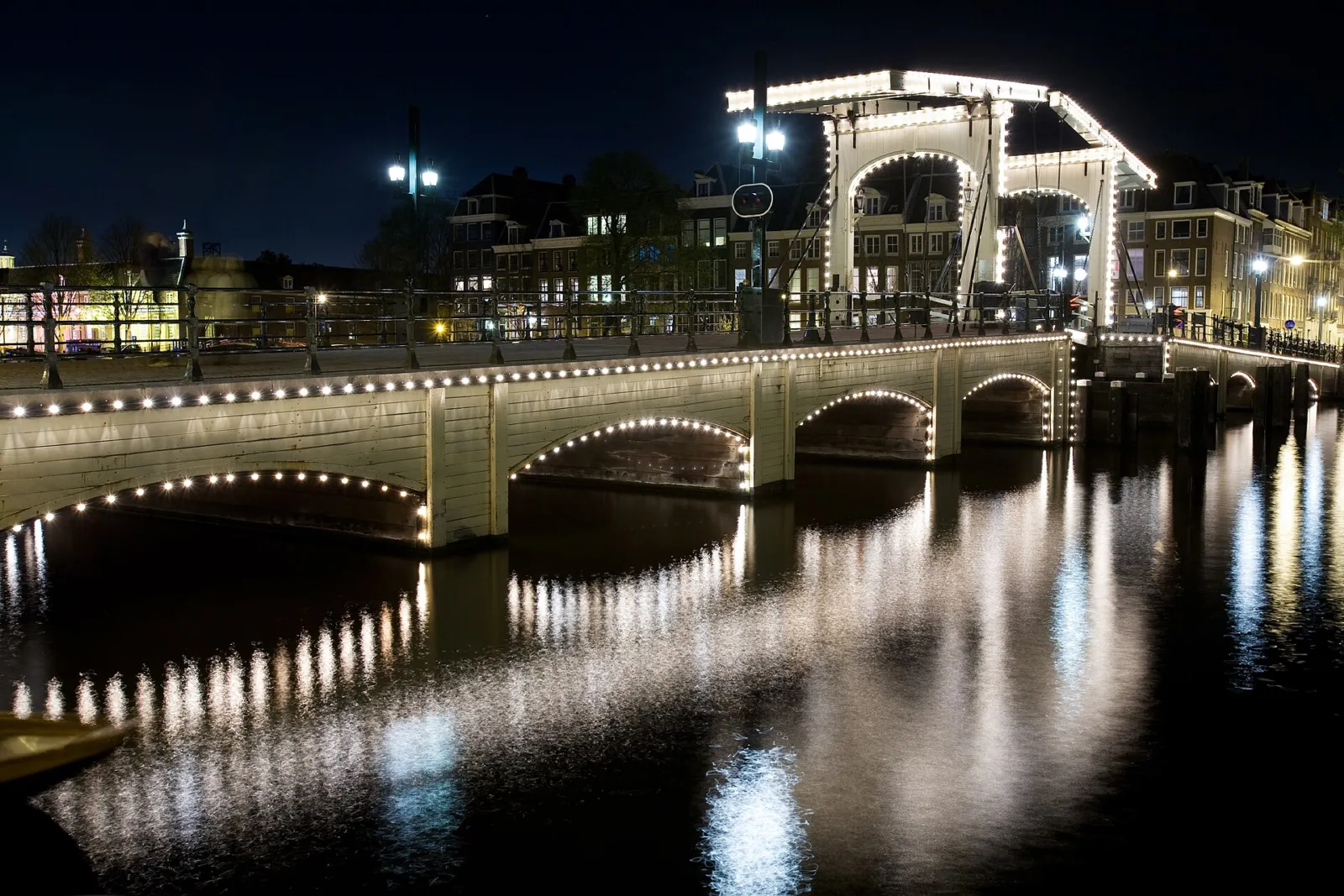 Magere Brug iluminado de noche sobre el río Amstel