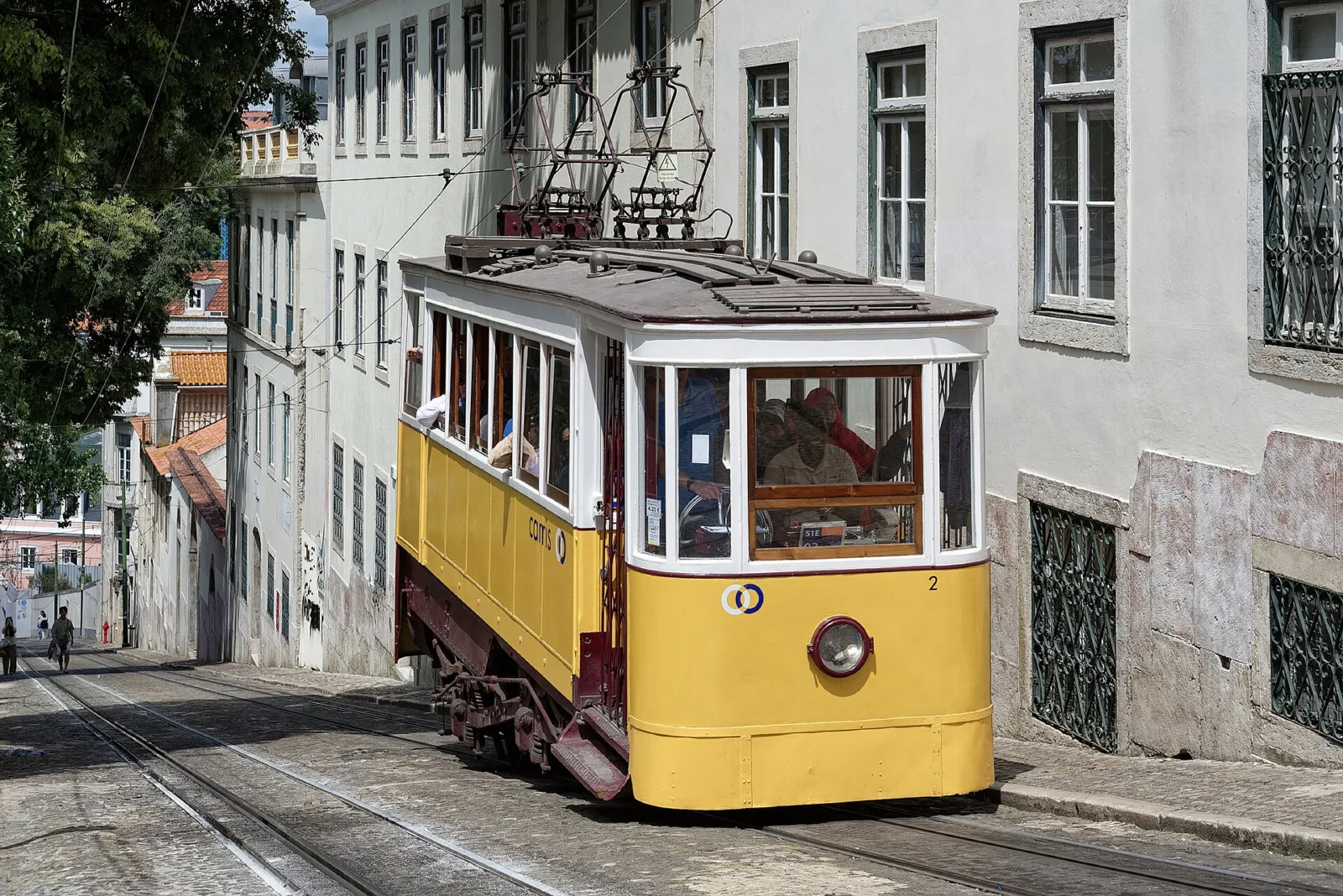 Funicular amarillo del Elevador da Glória subiendo por una calle empinada de Lisboa