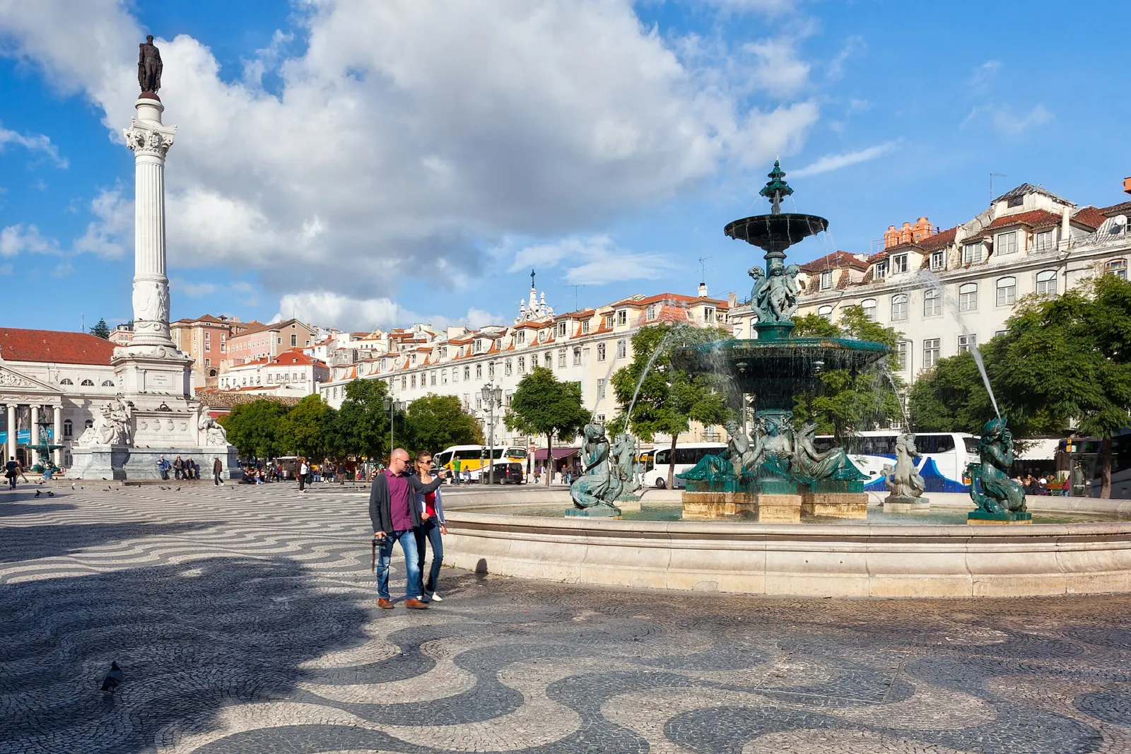 Fuente barroca, columna y pavimento ondulado de la plaza del Rossio en Lisboa con cielo azul