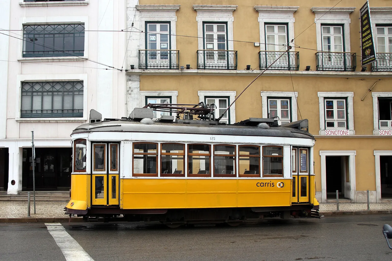 Tranvía amarillo tradicional circulando por una calle del centro de Lisboa delante de edificios antiguos
