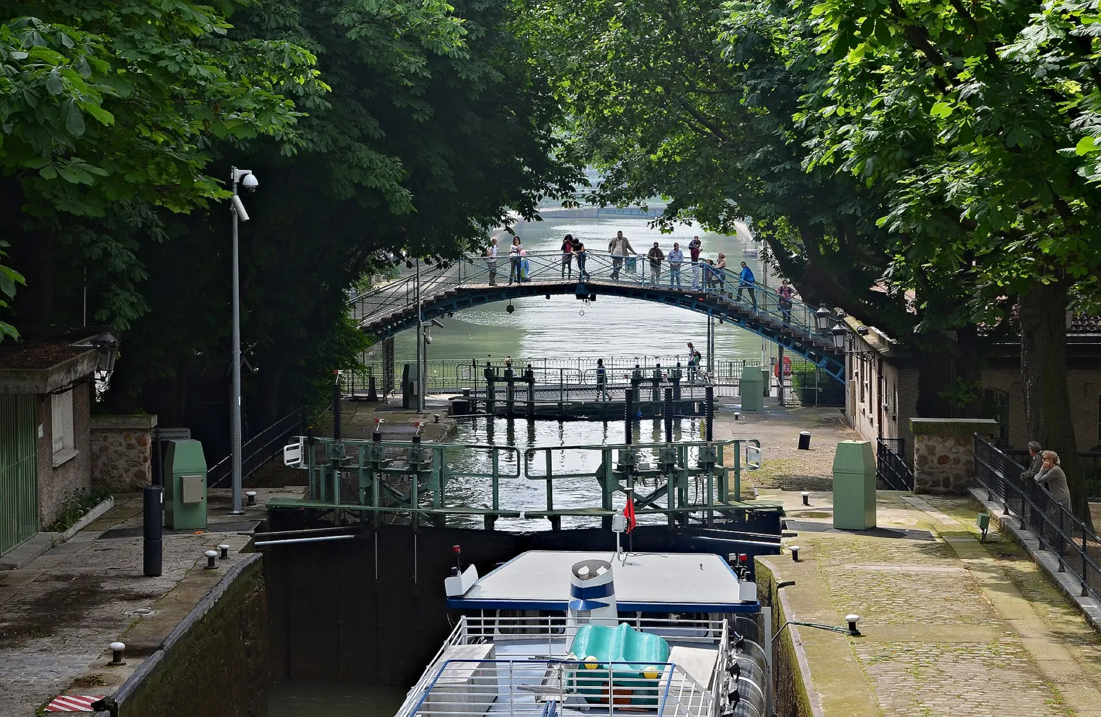 Esclusas y pasarela arqueada del Canal Saint-Martin rodeadas de árboles en París