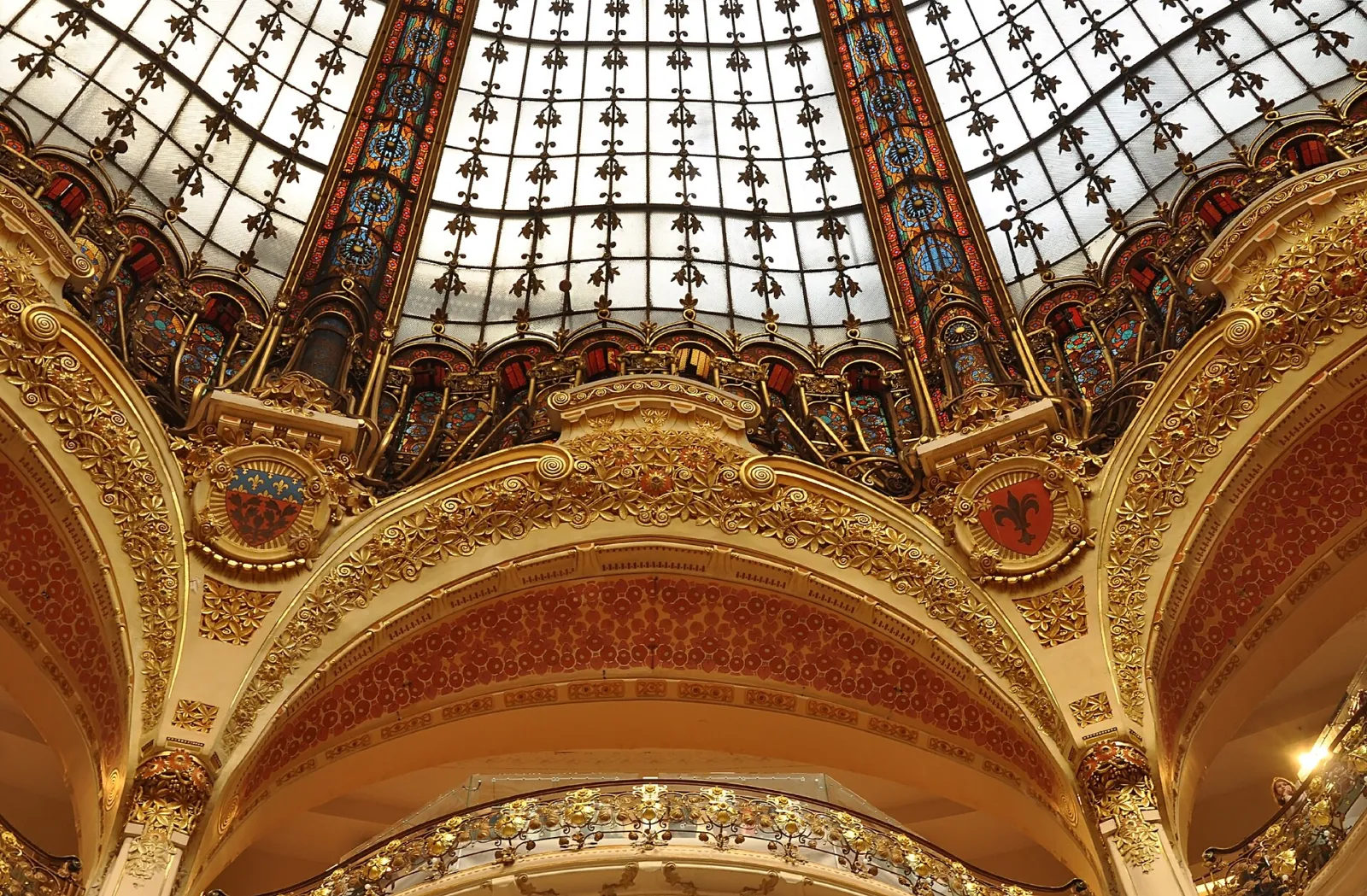 Cúpula de vidrieras modernistas y dorados de las Galeries Lafayette del bulevar Haussmann vista desde abajo