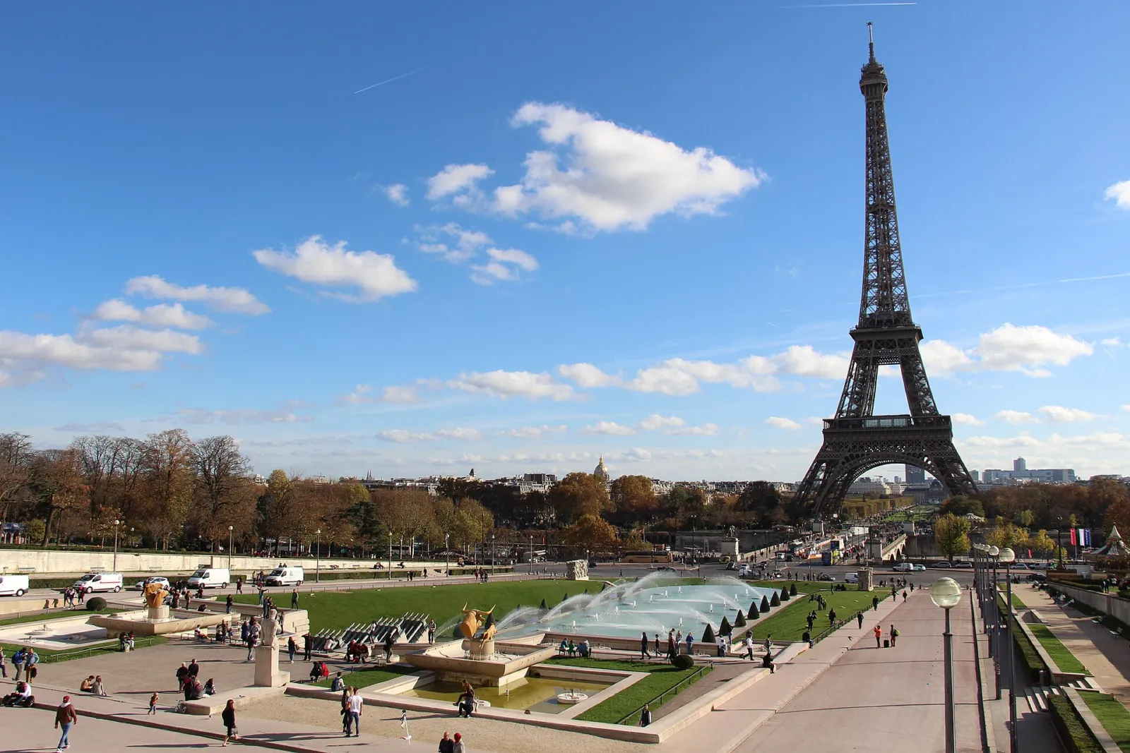 Los jardines del Trocadéro con sus fuentes y la Torre Eiffel al fondo bajo un cielo azul con nubes