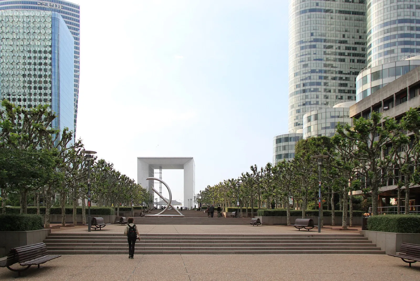 La Grande Arche de La Défense al fondo de la explanada, flanqueada por rascacielos y árboles