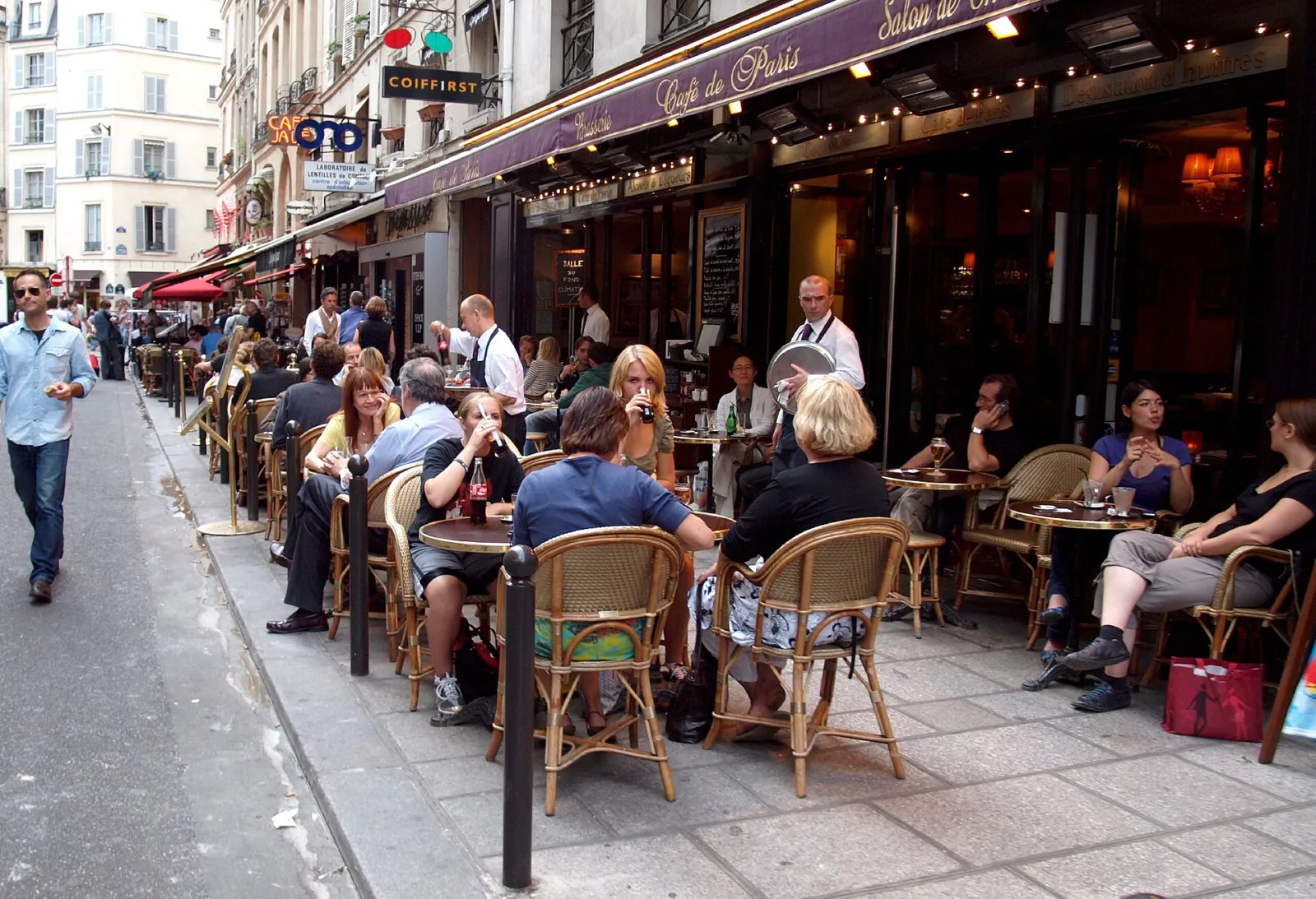 Terraza de café en la rue de Buci con mesas y sillas de mimbre en París